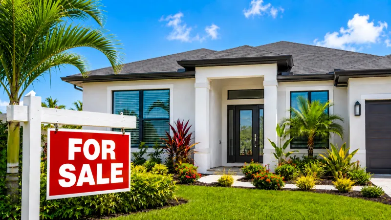 Modernes Haus im Südwesten Floridas mit Verkaufsschild und tropischer Bepflanzung