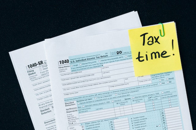 Tax return form with a yellow note that reads Tax Time attached to the upper right corner
