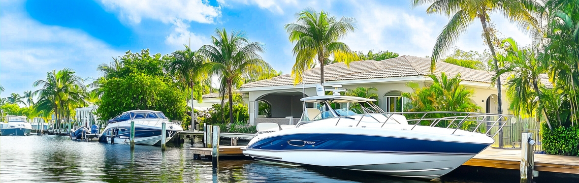 A canal in Southwest Florida lined houses for boaters and sports boats docked along private piers.